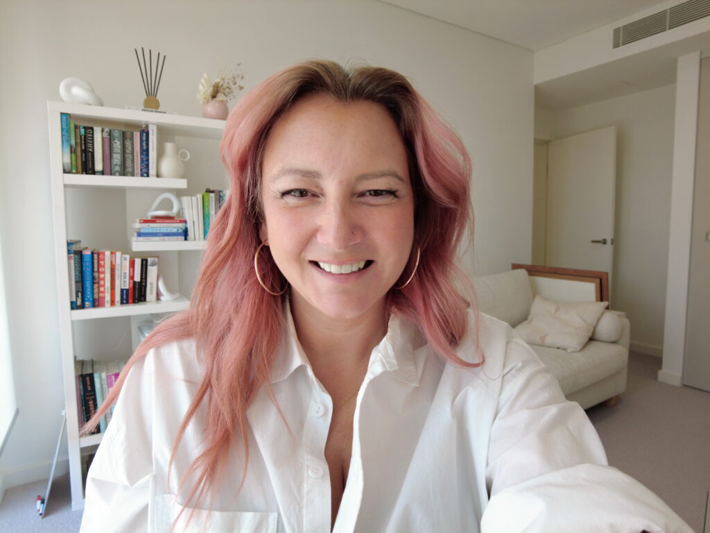 Leisa Wood - The Marketing Mentor Australia About Page. Leisa is looking at the camera smiling with a bookcase in the background.